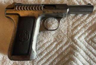 Vintage Savage Arms semi-automatic pistol with black checkered grips featuring an Indian head emblem, original slide markings, and visible finish wear from age.